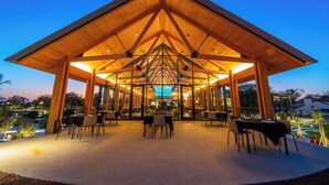 An outdoor dining area with a wooden roof and glass walls, featuring tables and chairs arranged for guests. - Evermore Orlando Resort (Orlando)