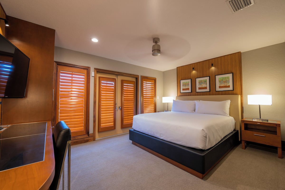 A hotel room with a bed, desk, and chairs.