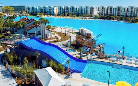 A resort with a large pool, a water slide, and a beach area.