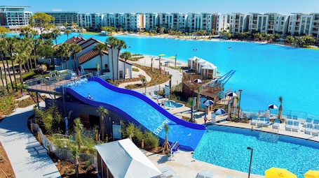 A resort with a large pool, a water slide, and a beach area.