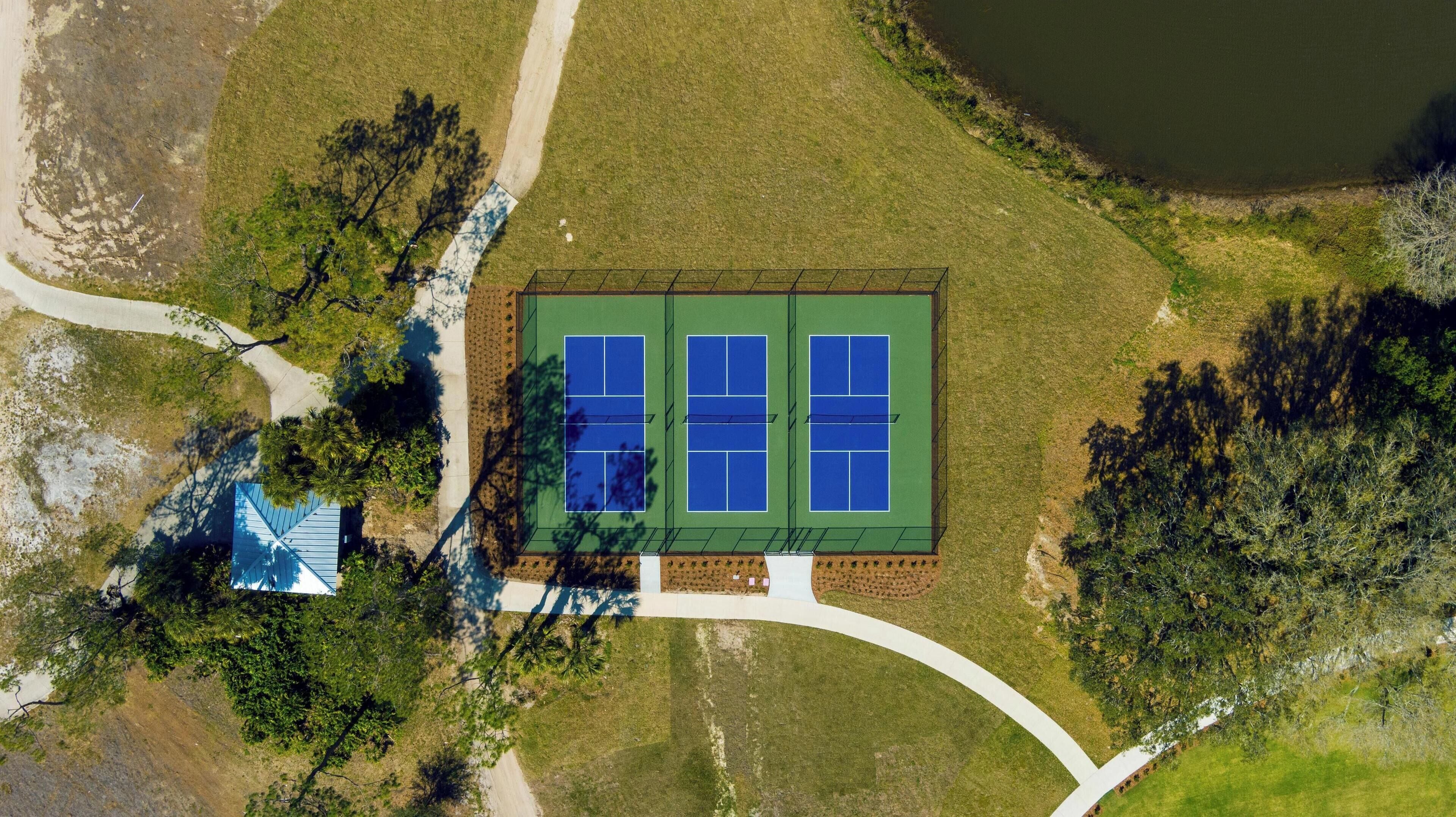 An aerial view of a tennis court surrounded by trees and a small building.