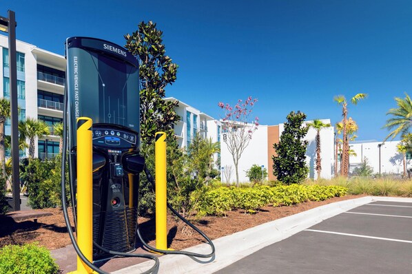 A Siemens electric vehicle charging station in a parking lot with a modern building in the background.