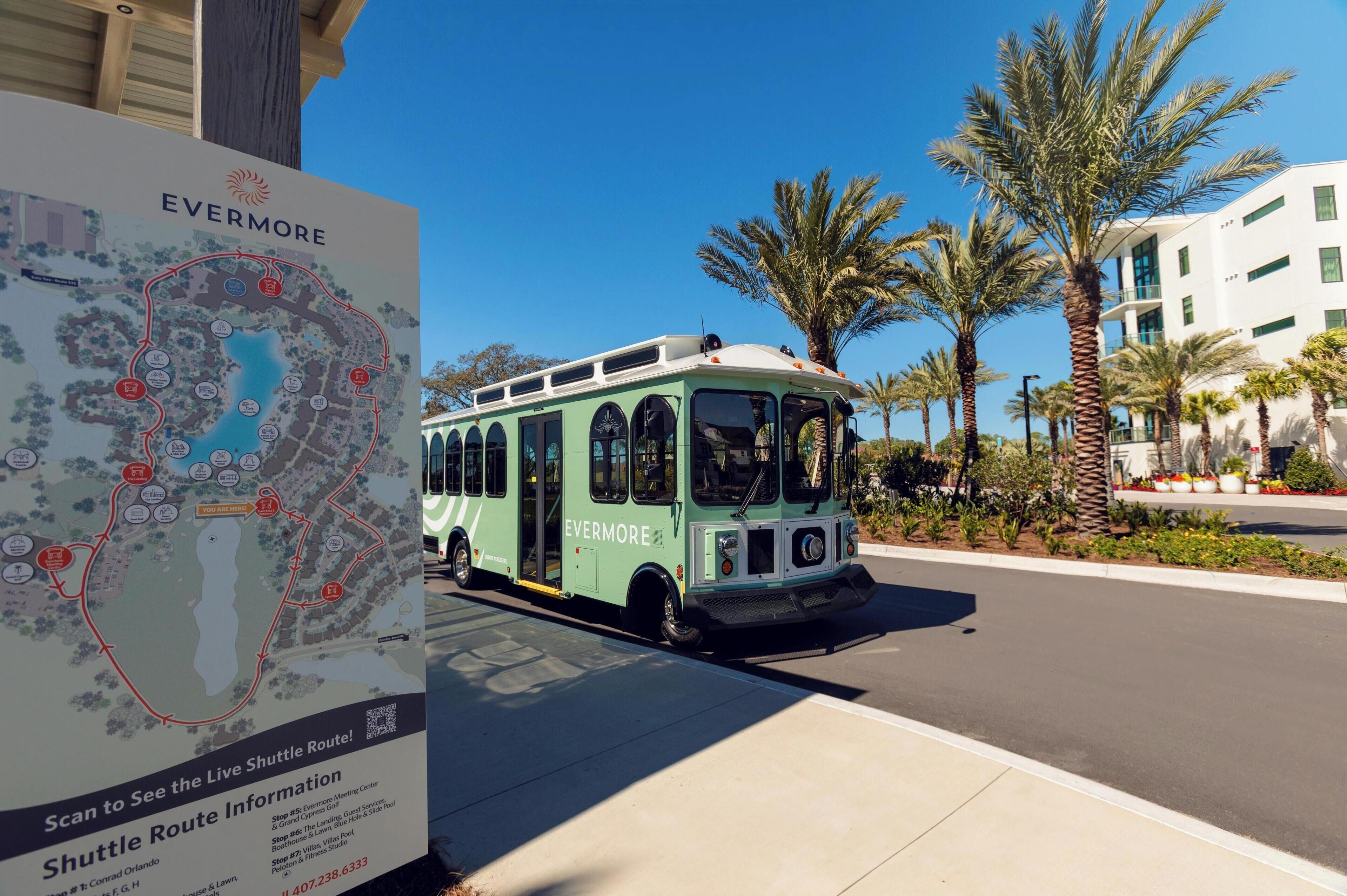 A green shuttle bus parked beside a signboard with a map and route information.