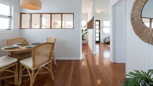 A dining area with wicker furniture, a hanging light fixture, and a large mirror on the wall. - Boho Beach Lux 250 Meters to Burleigh Sands (Burleigh Heads)