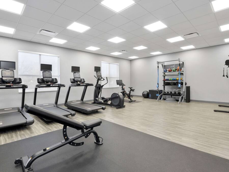 Un gimnasio con cintas de correr, elípticas y equipo de levantamiento de pesas.
