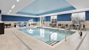 A swimming pool with clear water, surrounded by lounge chairs and tables, and a staircase leading to an upper level. - Hampton Inn By Hilton Cornwall (Cornwall)