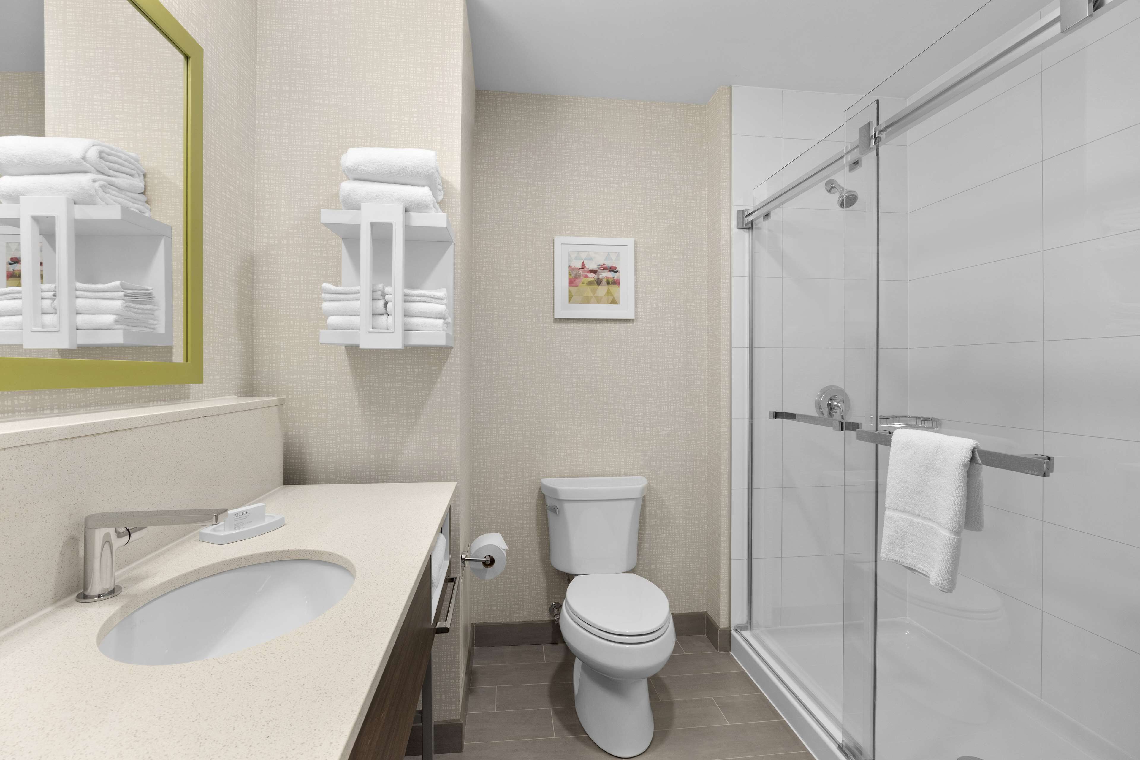A modern bathroom with a sink, toilet, and glass shower stall.
