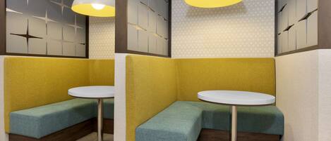 A corner seating area with a round table, cushioned benches, and pendant lighting.