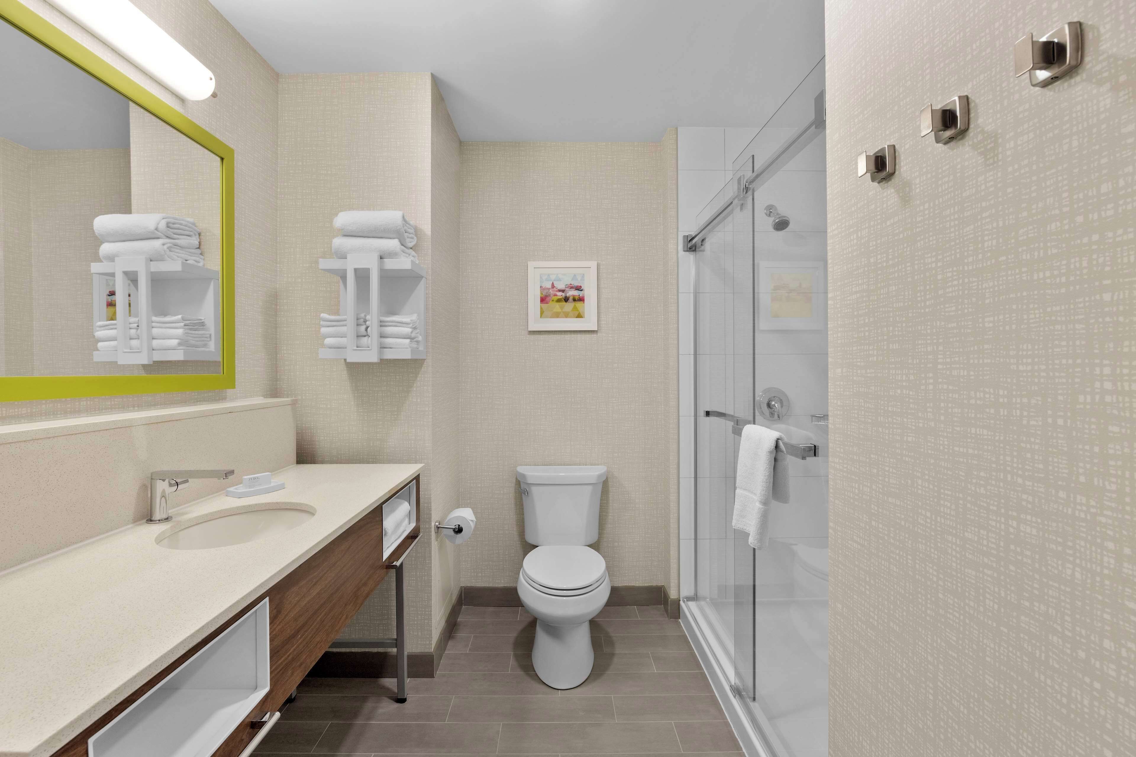 Un baño moderno con lavamanos, inodoro y ducha.