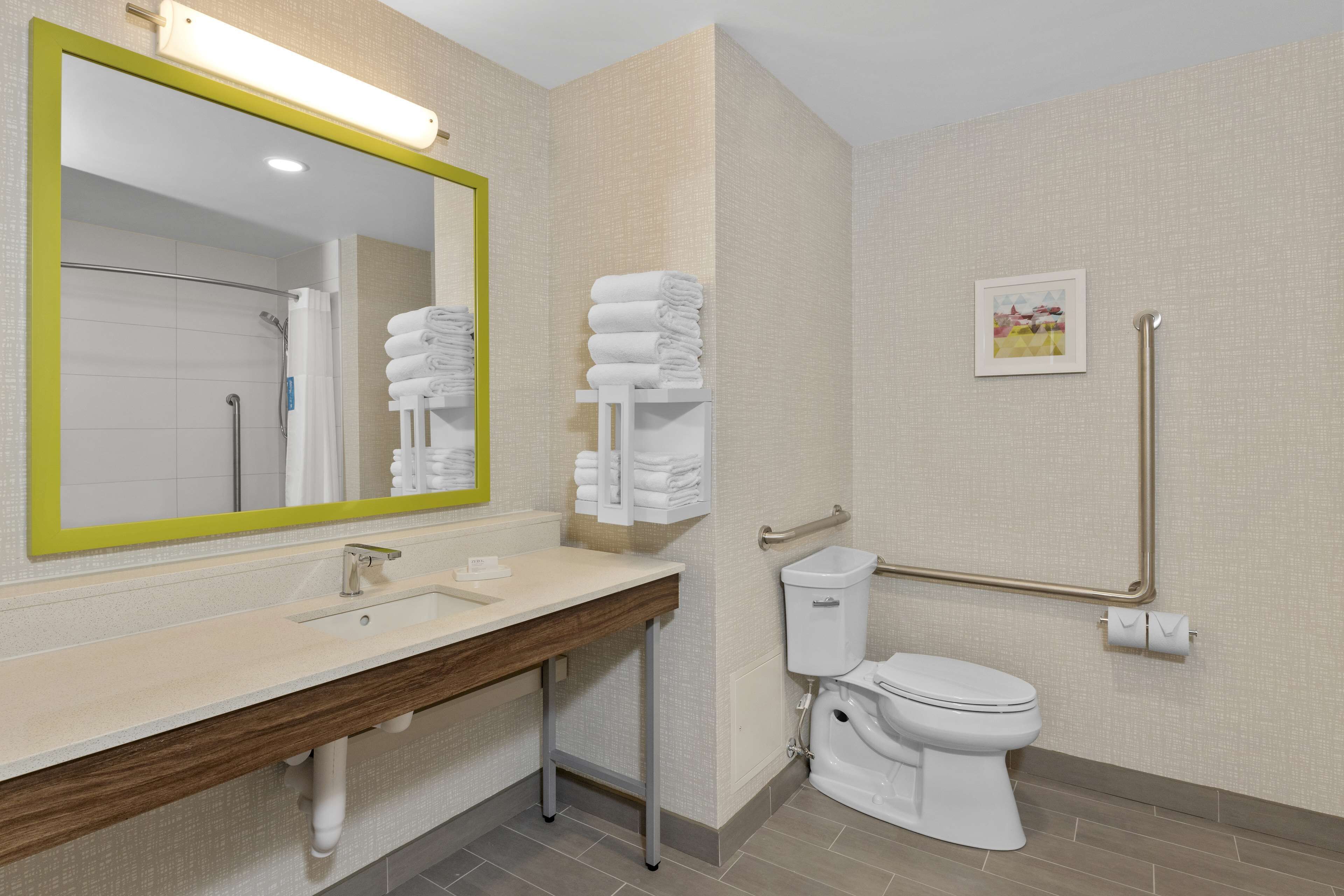 Een moderne badkamer met een grote spiegel, een wastafel, een toilet en een handgreep.