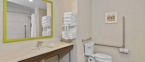 Une salle de bain moderne avec un grand miroir, un lavabo, des toilettes et une barre d’appui.