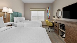 A hotel room with two beds, a desk with a chair, a television, and a window with a view.