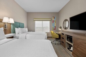 A hotel room with two beds, a desk with a chair, a television, and a window with a view.