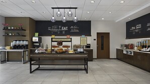A modern breakfast area with a coffee station, breakfast sign, and a counter with food items. - Hampton Inn By Hilton Cornwall (Cornwall)