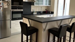 A modern kitchen with a central island, stainless steel appliances, and a bar area with chairs.