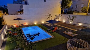 A rooftop pool area with a hot tub, lounge chairs, and a barbecue grill.