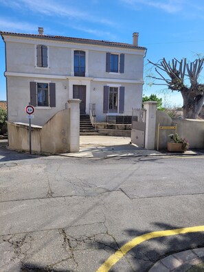 A two-story building with a gated entrance, a sign indicating a 3.5 km distance, and a directional sign for 'La Poste'.