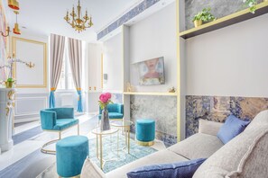 A modern living room with a sofa, two armchairs, a coffee table, and a TV. - Merveil - Luxury Suite - Notre-Dame - Saint Louis (Paris)