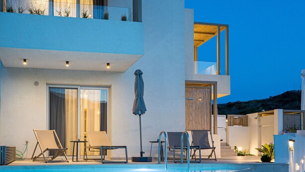 A modern poolside area with lounge chairs, a table, and a covered umbrella.