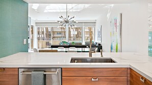 Una cocina moderna con una isla central, pileta de acero inoxidable y muebles de madera.