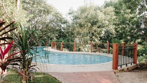 Une piscine entourée d’une clôture, avec un chemin menant à celle-ci.