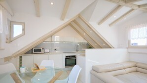 A compact kitchen with modern appliances, a glass dining table, and a beige sofa. - Hedera Estate, Hedera A22 (Dubrovnik)