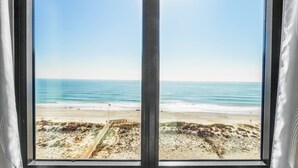 Vista sulla spiaggia attraverso una finestra con un pontile di legno e una bandiera.