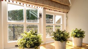 A kitchen with a wooden countertop, two potted plants, and a window with a view of a garden. - The Coach House at Lackington Farm (Dorchester)