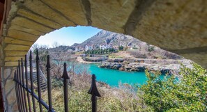 A stone archway overlooking a turquoise lake with buildings in the background.