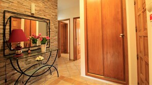 A hallway with a wooden door, a mirror, and a glass table with flowers.