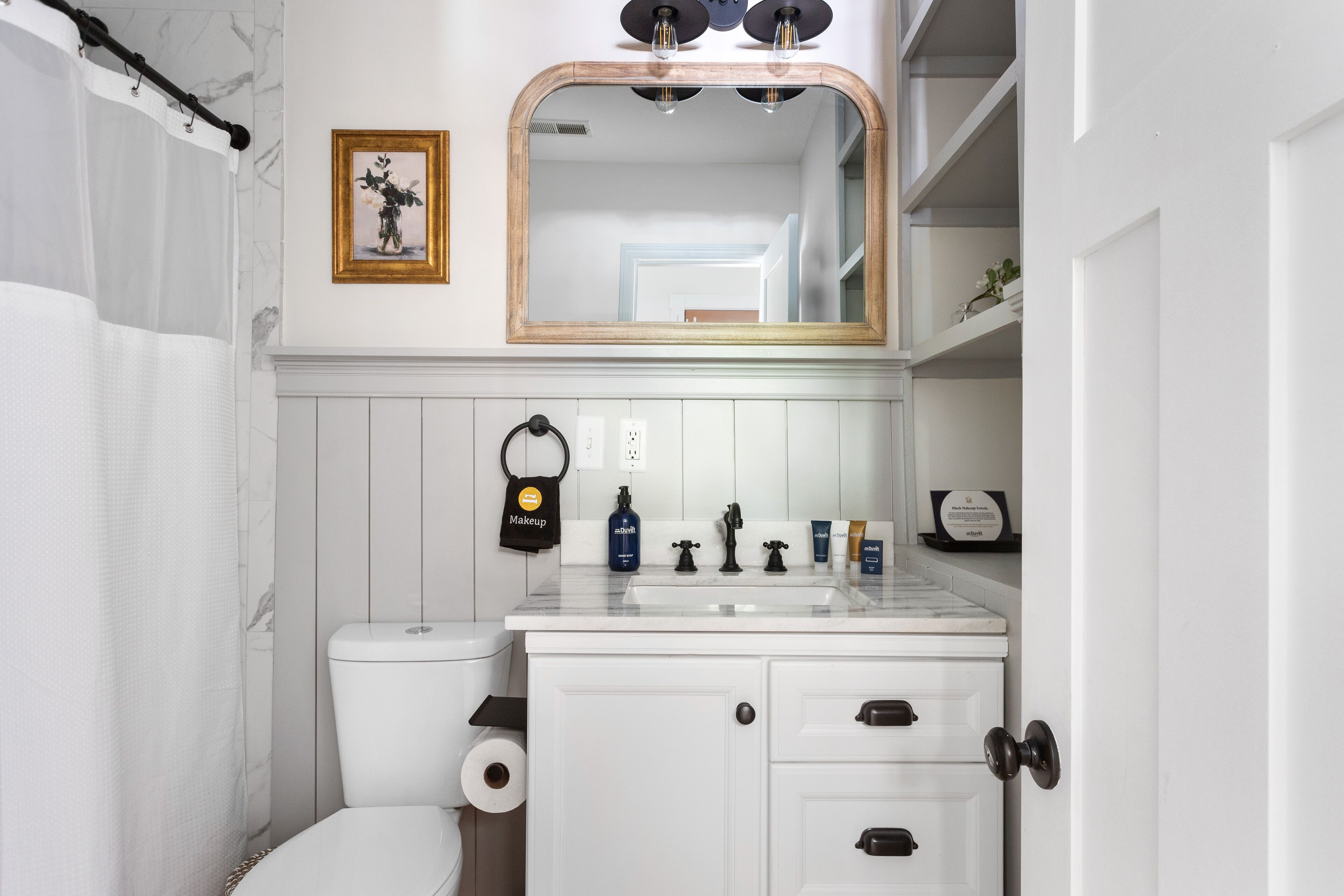 A bathroom with a toilet, sink, and mirror.