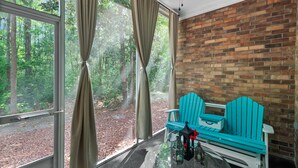 Una habitación con pared de ladrillo, ventanas amplias y un banco.