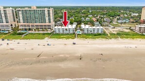 Ein Strandhotel mit mehreren Gebäuden, einem Pool und einer Strandfläche.