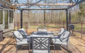 Une terrasse extérieure dotée d’une pergola, d’une table avec des chaises et d’un barbecue.