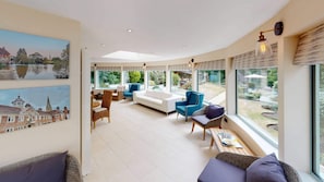 A spacious living area with a curved ceiling, large windows, and a view of the outdoors.