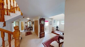 Un intérieur spacieux agrémenté d’un magnifique escalier, d’une grande horloge en bois et d’un coin repas aménagé dans un style traditionnel.