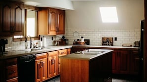 Una cucina con mobili in legno, lavastoviglie, lavello e una finestra che offre luce naturale.
