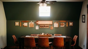 Una sala da pranzo con un tavolo imbandito per quattro persone, circondato da sedie e un ventilatore a soffitto.