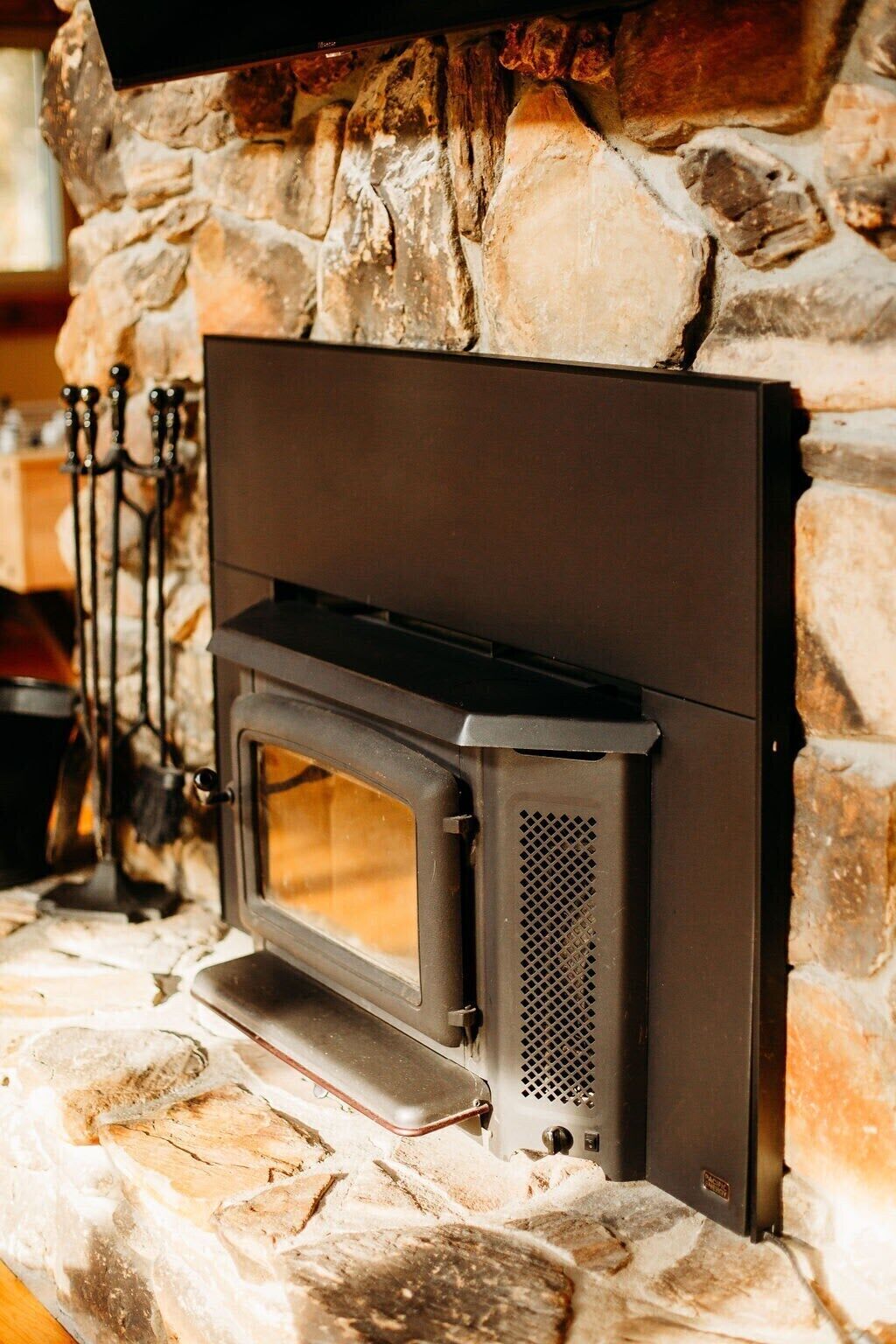 Une cheminée en pierre avec un poêle à bois noir au design moderne.