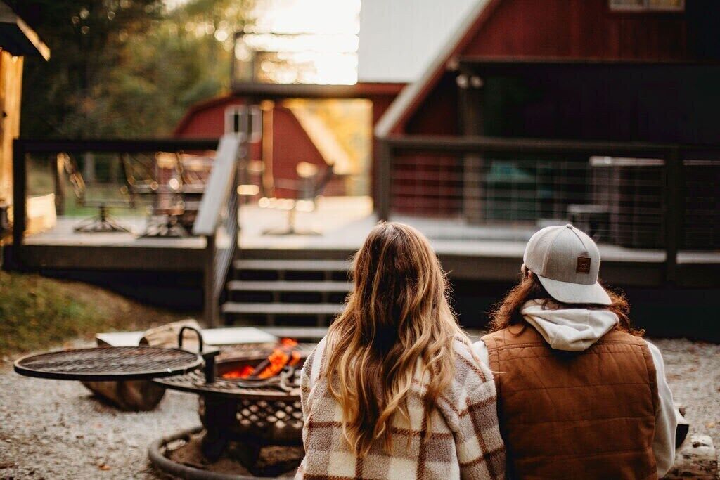 Dos personas sentadas en una mesa al aire libre, con un brasero al frente.