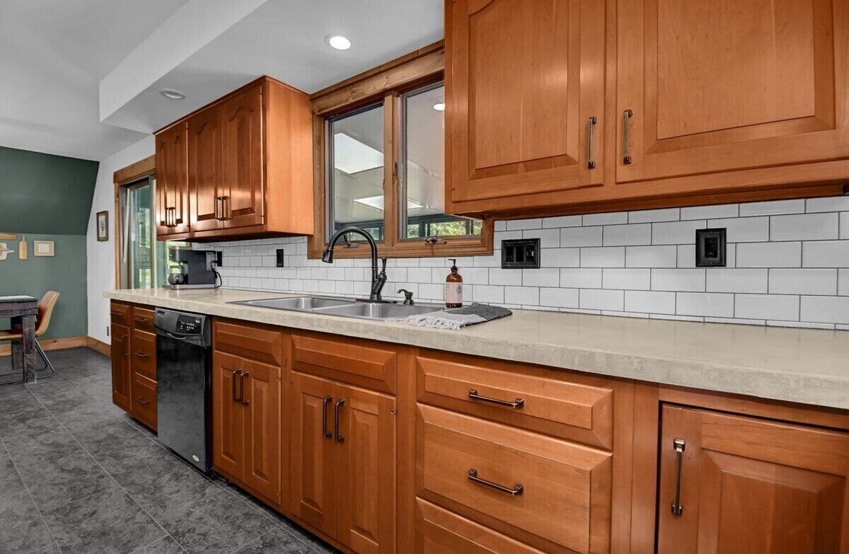 A kitchen with wooden cabinets, a dishwasher, a sink, and a window.