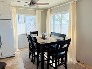 A dining area with a table, chairs, a ceiling fan, and a refrigerator. - Beachside condo #A with 2bd /2 bath (Carlsbad)