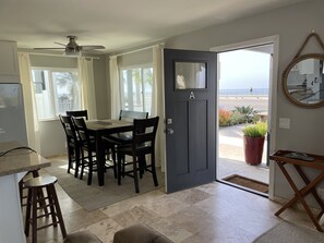 A dining area with a table and chairs, a ceiling fan, a door labeled 'A', and a view of the beach through an open door. - Beachside condo #A with 2bd /2 bath (Carlsbad)