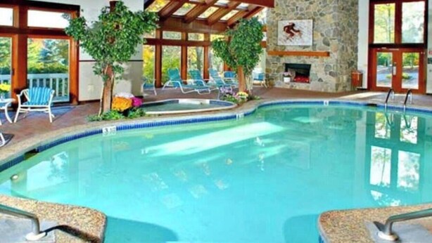 Una piscina interior amb paret de pedra, una llar de foc i seients per relaxar-se.