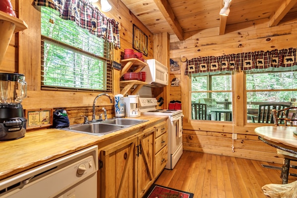 Enjoy cooking in this cabin-style kitchen with a dishwasher, sink, stove, and microwave.