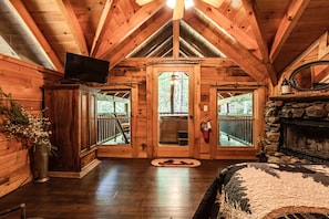 Cozy cabin with a fireplace, TV, and large window offering a view.