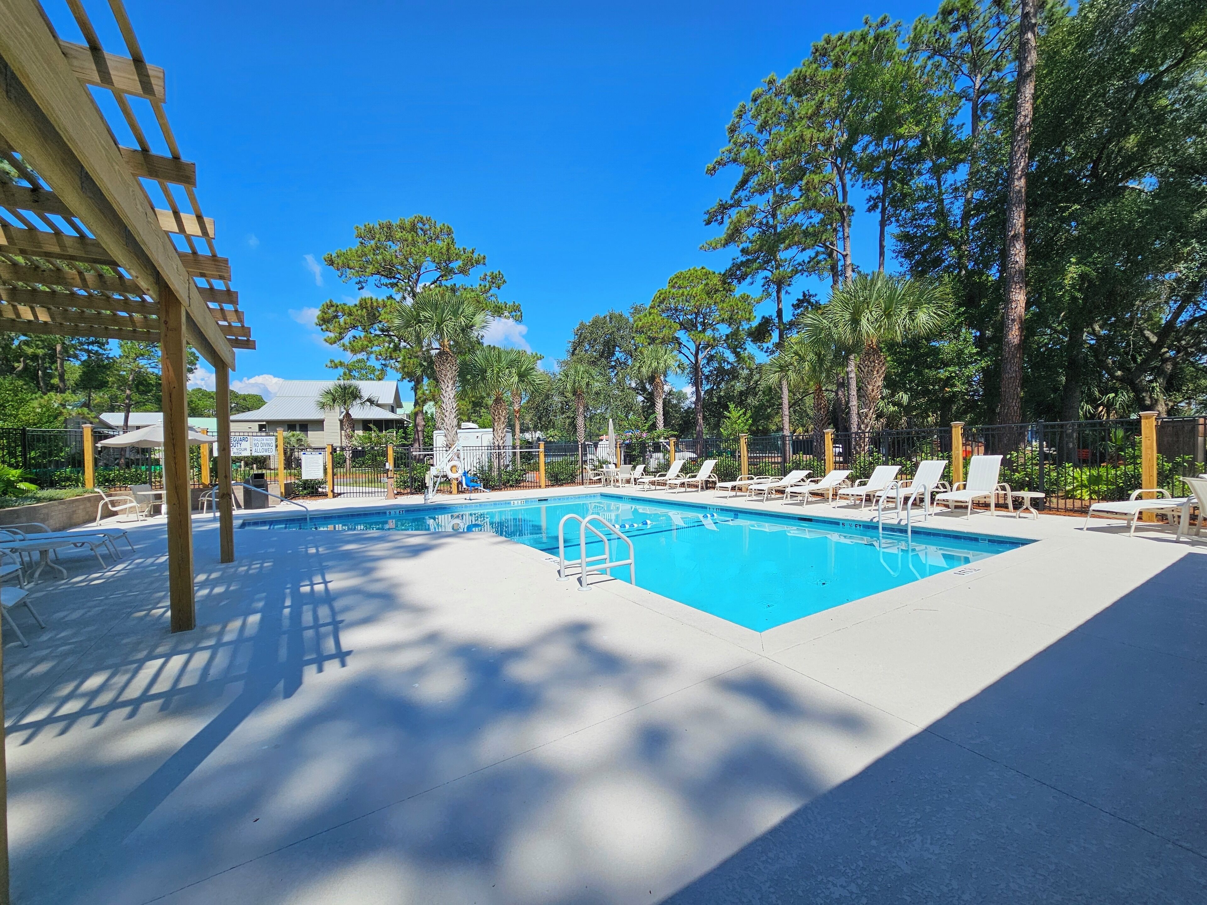 A pool area with lounge chairs and a wooden pergola.