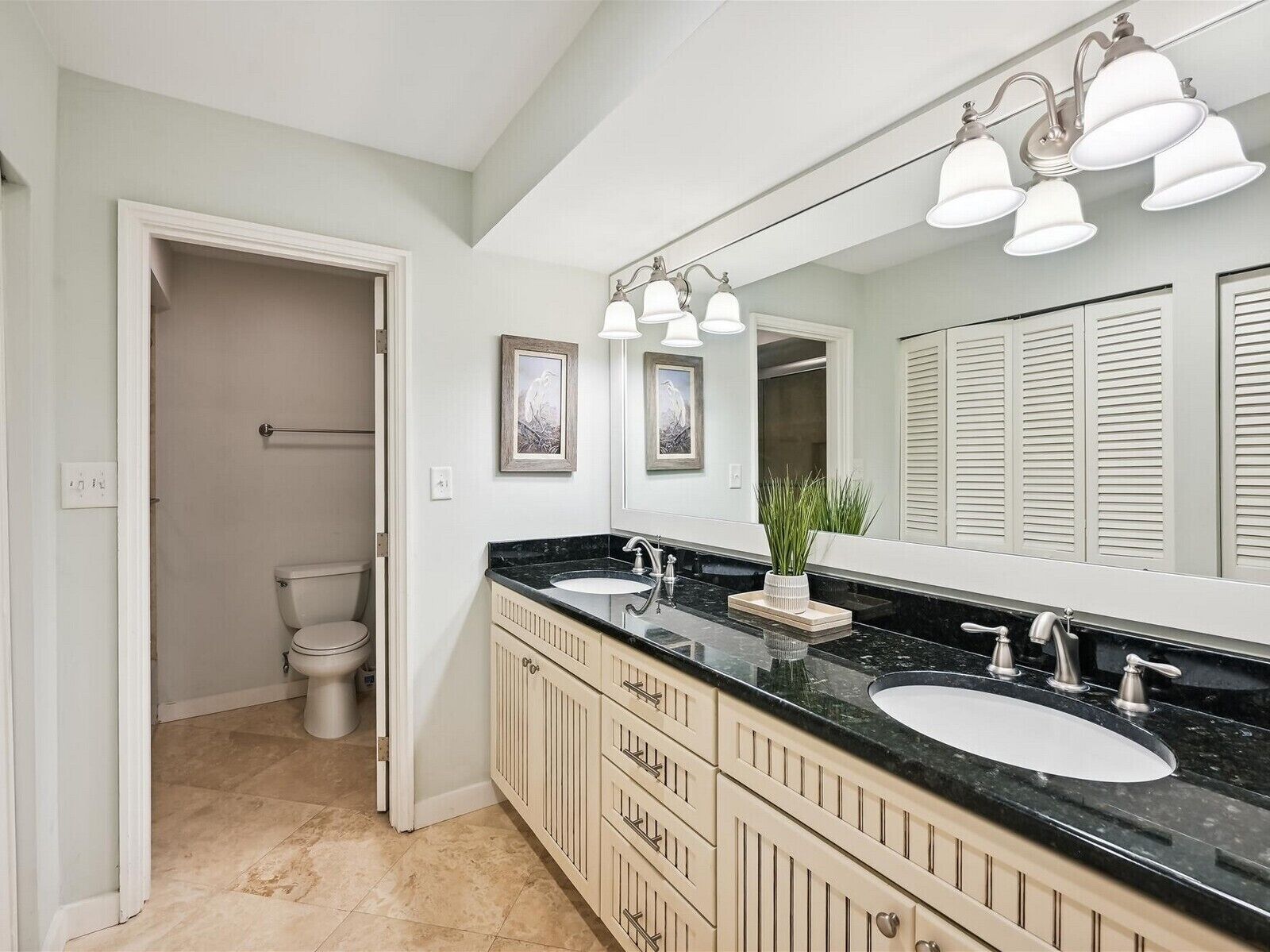 A bathroom with two sinks, a large mirror, and a toilet.