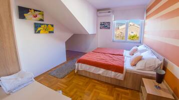 Une chambre avec deux lits, une fenêtre donnant sur un beau paysage et des œuvres d’art accrochées aux murs.