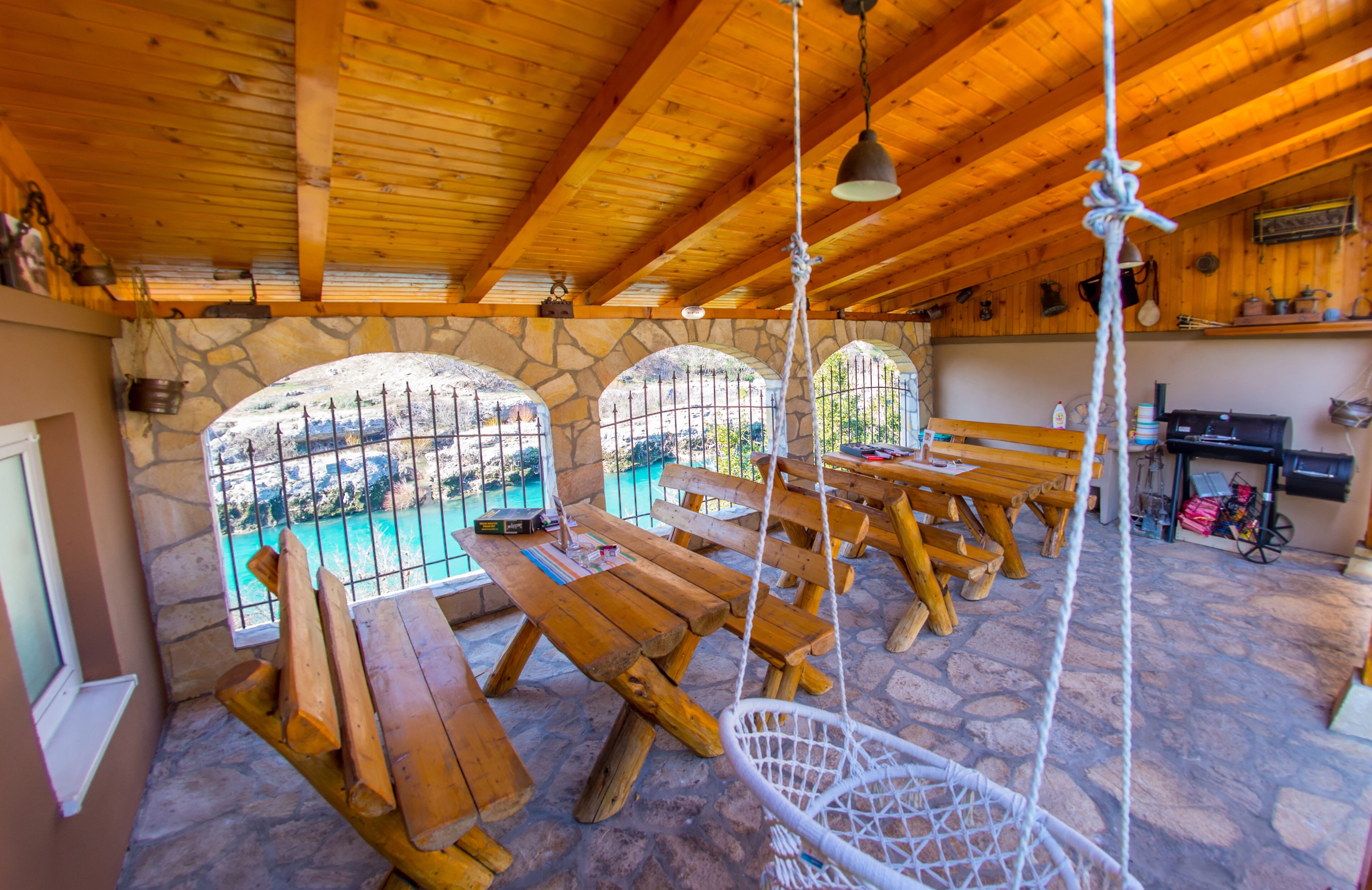 Un intérieur rustique avec des murs en pierre, des bancs en bois et un luminaire suspendu.